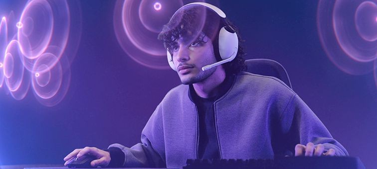 Геймер за комп’ютером у білій гарнітурі Sony INZONE H3 з мікрофоном на штанзі.